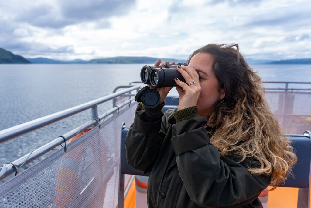 Young Woman Watching birds with binoculars during Wildlife Cruise