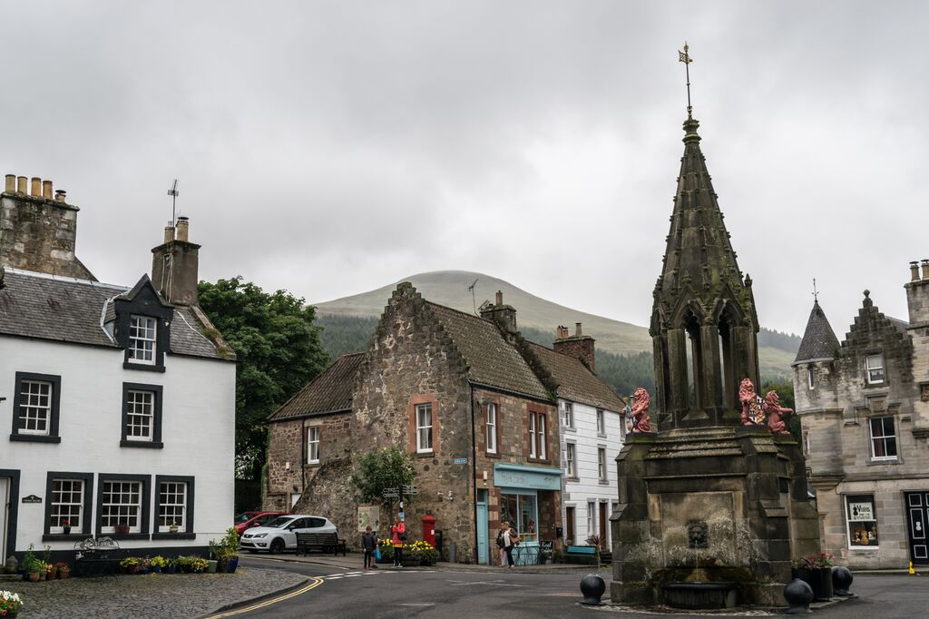 Town centre of Falkland with traditional stone houses and a tall impressive fountain in the centre