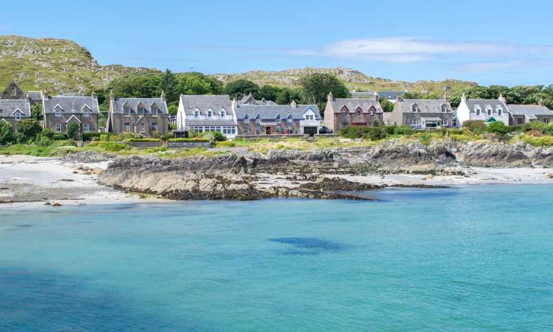 Isle of Iona with a sandy beach, turquoise waters gently lapping the shore, and traditional stone houses