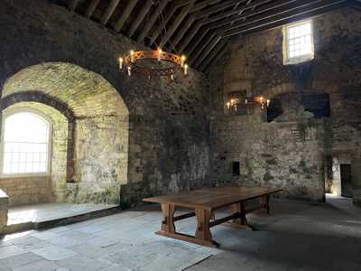 Doune Castle interior room featuring a stone arch window, wooden table, and heavy rounded wooden lights