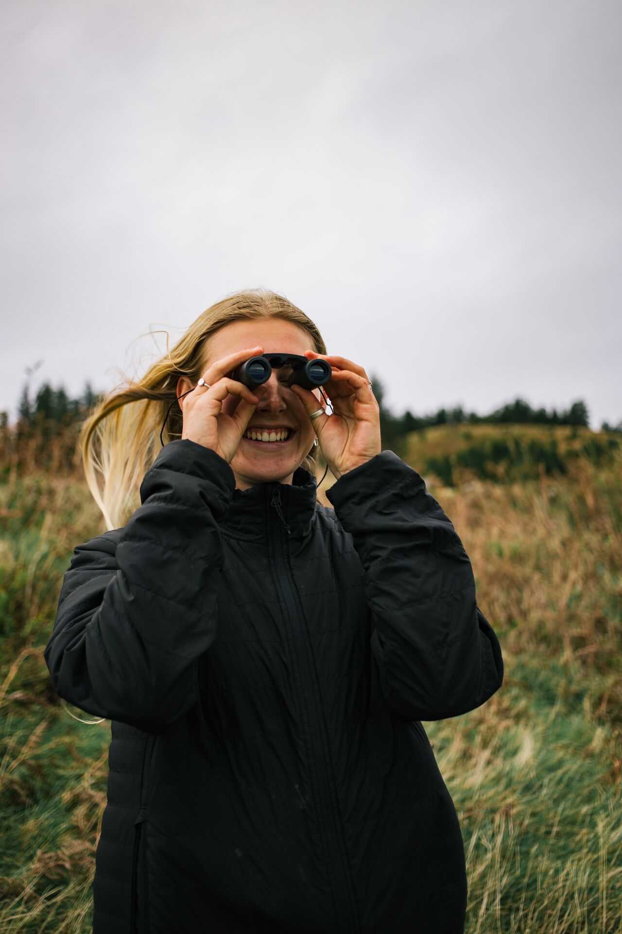 Young female watching birds at Tormore Forest with binoculars