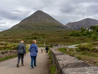 A couple exploring sligachan bridge on isle of skye with mood skies and hills in background
