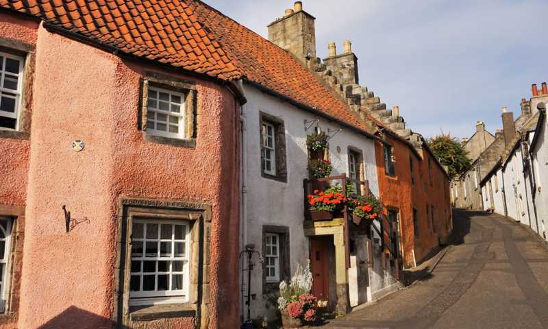 Narrow alley in quaint Culross village with colourful housefronts and flower pots in the windows