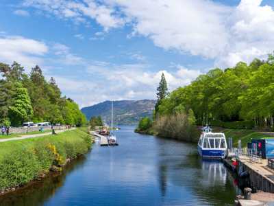 Caledonian Canal at Fort Augustus with boats moored, leading to the vast waters of Loch Ness in summer