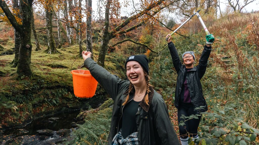 Two young women with working tools walking through Tormore Forest