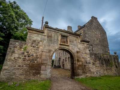 Dramatic entrance archway of Midhope Castle, with its weathered stone frame and surrounding landscape