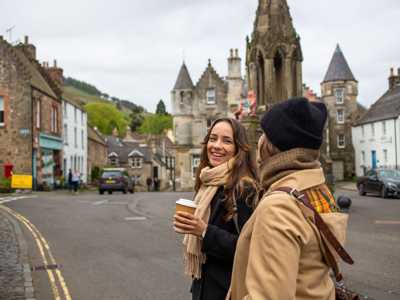Two young women walking past the Bruce Fountain in Falkland, with charming village views