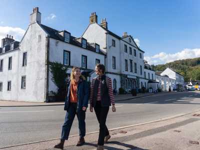 Two female travellers walking through the street in Inveraray with whitewashed houses int he background