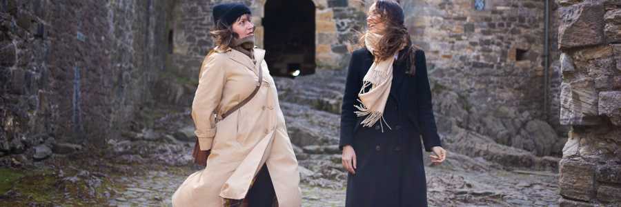 Two young women exploring the inner courtyard of Blackness Castle, surrounded by stone walls