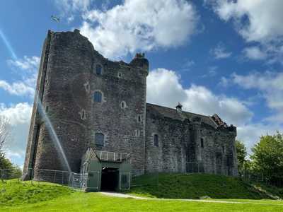 Sunny view of Doune Castle exterior, highlighting its impressive stone walls and turrets