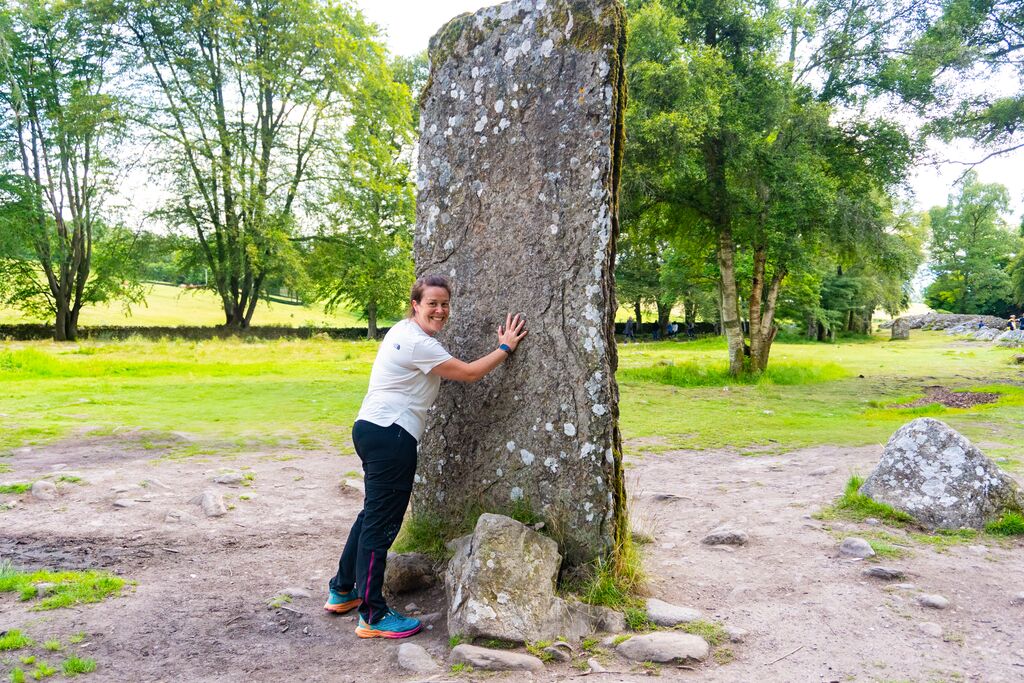 Woman smiling and leaning against Clava Cairns Stone